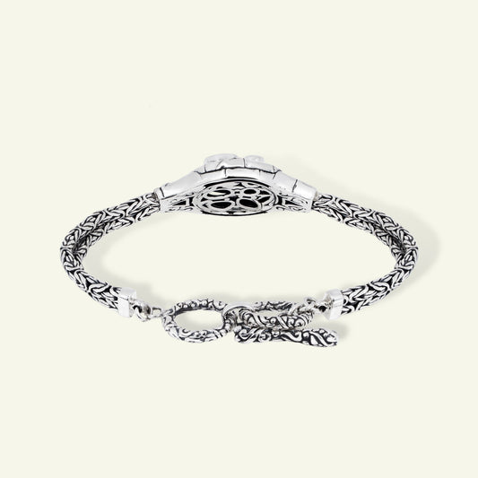 Silver bracelet with intricate design on a white background