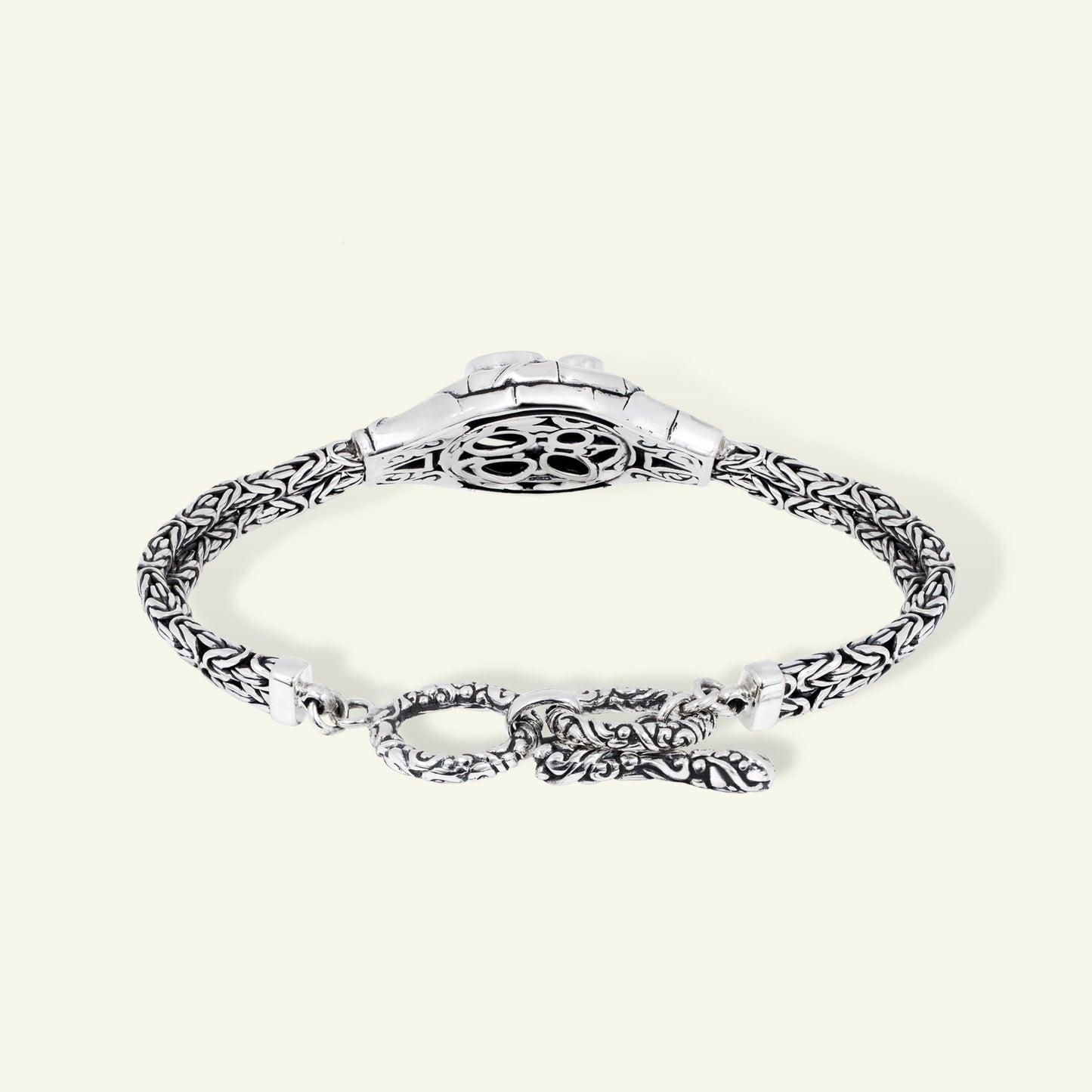 Silver bracelet with intricate design on a white background