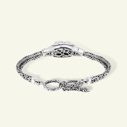 Silver bracelet with intricate design on a white background